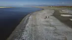 Sepasang suami istri berjalan di sepanjang tepi air yang surut setelah level air terendah terlihat di Great Salt Lake (6/9/2022). Gelombang panas terik memecahkan rekor di Utah, di mana suhu mencapai 105 derajat Fahrenheit (40,5 derajat Celcius) pada hari Selasa, menjadikannya hari terpanas September yang tercatat sejak tahun 1874. (AP Photo/Rick Bowmer)