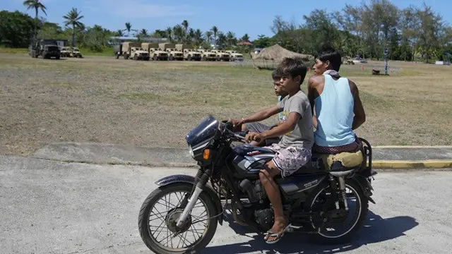 Warga Filipina mengemudikan motor melewati kendaraan militer Amerika Serikat di Pangkalan Angkatan Laut Camilo Osias di Santa Ana, Provinsi Cagayan, Filipina, pada 6 Mei 2024.