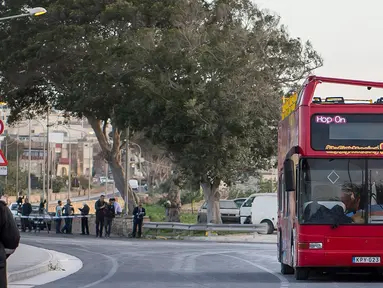 Petugas kepolisian berdiri dekat sebuah bus tingkat beratap terbuka yang menabrak dahan pohon di Zurrieq, Malta, Senin (9/4). Kejadian ini mengakibatkan dua orang tewas dan puluhan penumpang lainnya termasuk anak-anak terluka. (AP Photo/Rene Rossignaud)