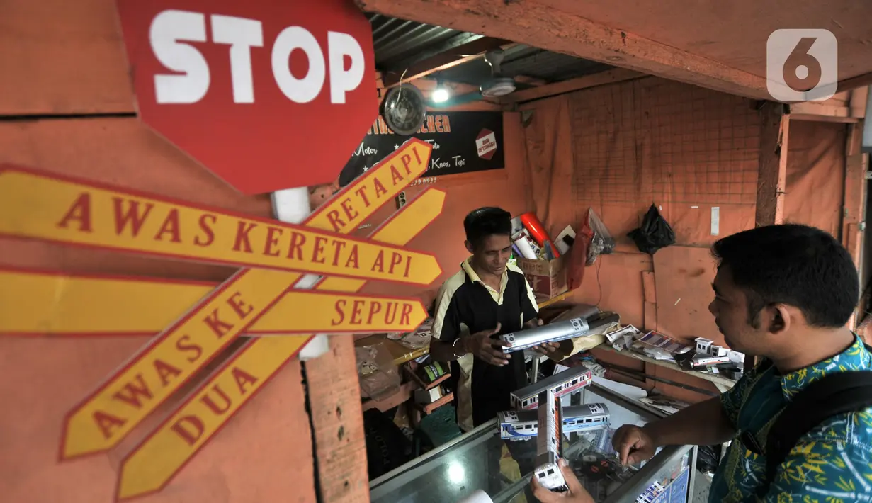 Iskandar (52) melayani pembeli miniatur kereta api di kawasan Manggarai, Jakarta, Kamis (21/11/2019). Untuk pembuatan, dalam sehari Iskandar mampu menghasilkan 5 gerbong miniatur kereta dengan dibantu satu pegawai. (merdeka.com/Iqbal S. Nugroho)