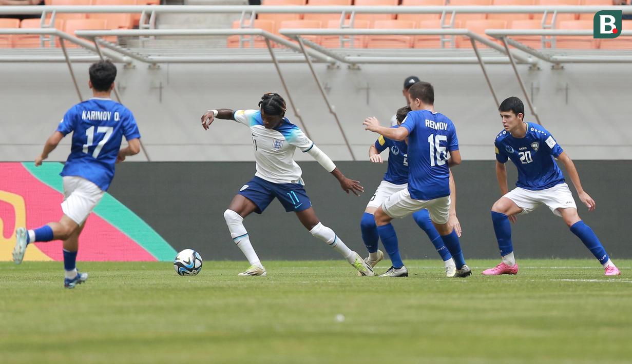 Pemain Timnas Inggris U-17, Joel Ndala, dikepung pemain Uzbekistan U-17 pada babak 16 besar Piala Dunia U-17 2023 di Jakarta International Stadium (JIS), Rabu (22/11/2023). Gerakan pemain muda Manchester City itu sukses merepotkan barisan pertahanan lawan. (Bola.com/M Iqbal Ichsan)