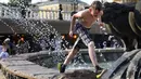 Seorang anak laki-laki mendinginkan dirinya dengan berlari melalui air mancur di Lapangan Manezhnaya dekat Lapangan Merah, Moskow, Rusia, Jumat (25/6/2021). Suhu tengah hari di Moskow mencapai 33 Celcius (91,4 Fahrenheit). (AP Photo/Alexander Zemlianichenko)
