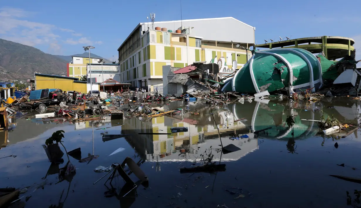 Orang-orang memeriksa kerusakan sebuah pusat perbelanjaan setelah gempa bumi dan tsunami menghantam Kota Palu di Sulawesi Tengah, Minggu (30/9). Dampak dari bencana tersebut melulunlantakkan bangunan dan ratusan jiwa meninggal dunia. (AP/Tatan Syuflana)