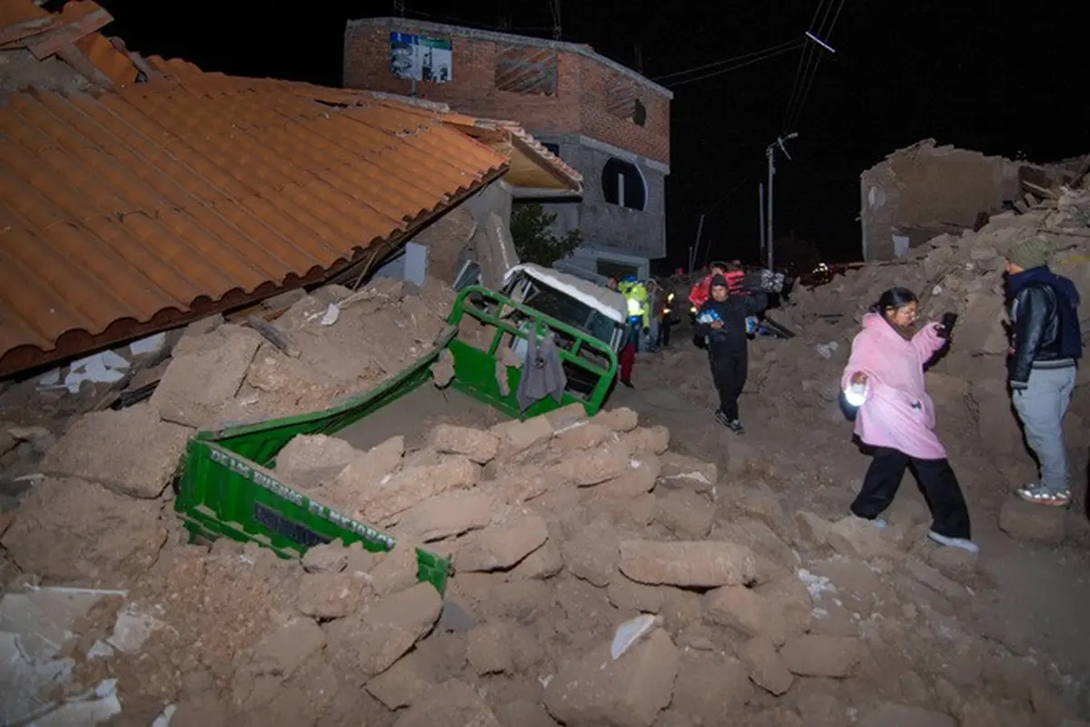 Warga berjalan di antara puing-puing rumah yang runtuh akibat gempa di Pumpuya, Peru, Minggu (19/7/2026), sehari setelah bencana tersebut terjadi.