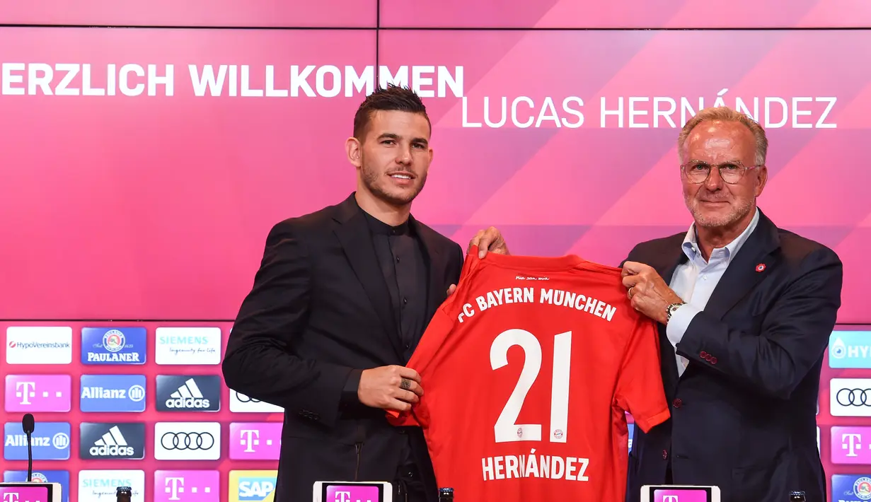 Bek baru Bayern Munchen, Lucas Hernandez berpose bersama CEO Bayern Munchen, Karl-Heinz Rummenigge sambil memegang jersey saat diperkenalkan secara resmi di Allianz Arena, Senin (8/7/2019). Pemain 23 tahun ini diikat kontrak selama lima tahun atau hingga 2024 oleh Bayern. (Christof STACHE/AFP)