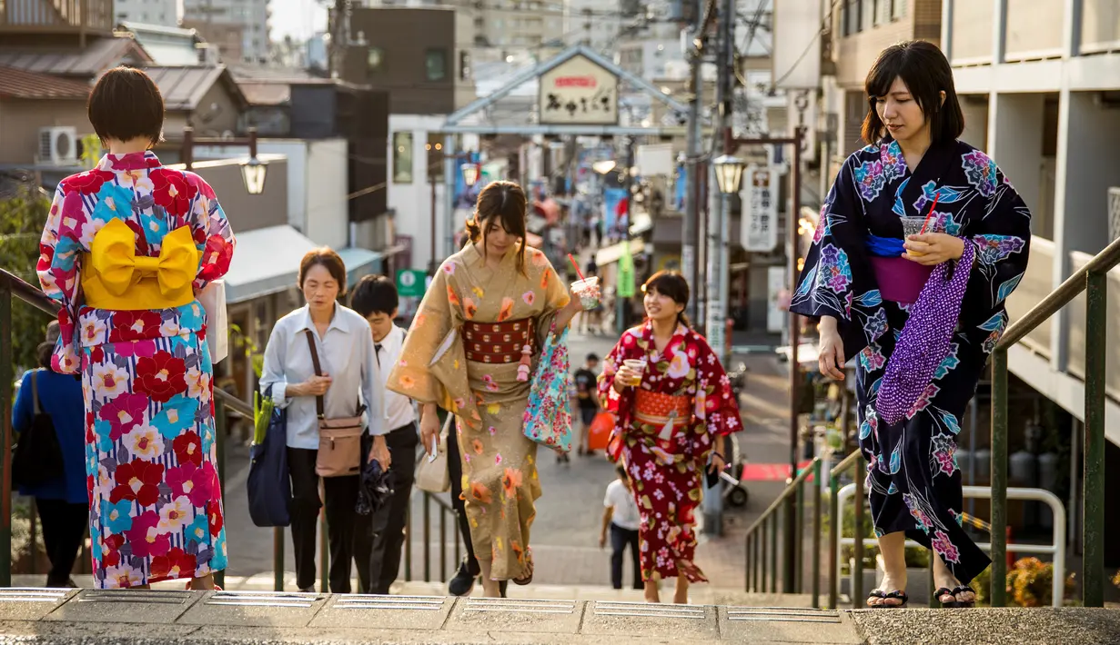 Sejumlah wanita memakai pakaian tradisional berjalan di sepanjang jalan perbelanjaan Yanaka Ginza di pusat Tokyo (30/9/2019). Wilayah Yanaka di ibukota Jepang dikenal sebagai salah satu yang paling kuno dan unik. (AFP Photo/Odd Andersen)