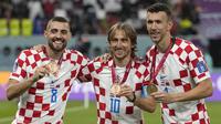 Tiga pemain Kroasia, Luka Modric (tengah), Mateo Kovacic (kiri), dan Ivan Perisic berpose dengan medali setelah meraih peringkat ketiga di Piala Dunia 2022. Ini merupakan kedua kalinya Kroasia meraih peringkat ketiga dalam perhelatan akbar empat tahunan ini, sebelumnya pada Piala Dunia 1998 Kroasia langsung menjadi tim peringkat ketiga dalam debut mereka di Piala Dunia. (AP Photo/Frank Augstein)