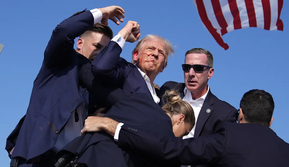 Ketika hendak meninggalkan panggung, Trump dilaporkan masih bisa mengepalkan tangan ke arah hadirin. (AP Photo/Evan Vucci)