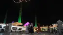 Orang-orang melewati bangunan masjid Faisal yang diterangi selama perayaan hari kelahiran Nabi Muhammad SAW atau Maulid Nabi di Islamabad, Pakistan, Senin (18/10/2021). Peringatan Maulid Muhammad tak hanya diperingati umat Islam di Indonesia, tapi juga di berbagai negara. (Farooq NAEEM/AFP)