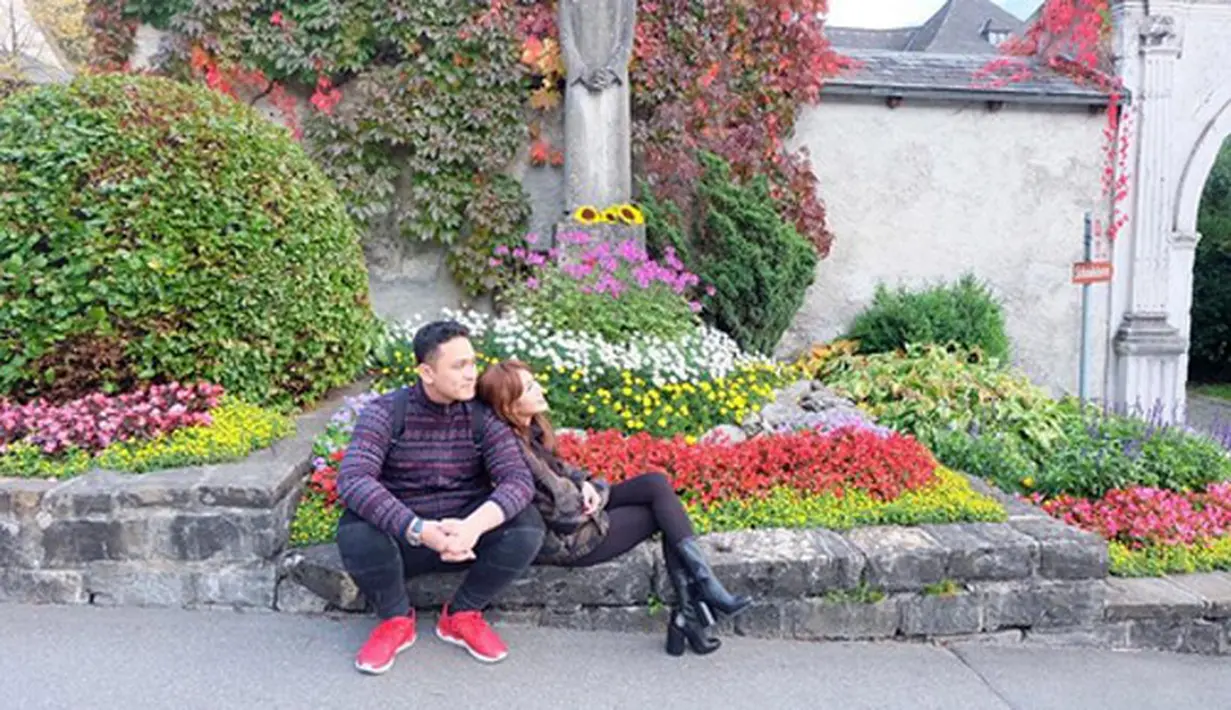 Presenter dan Adiez sedang bersantai. Dengan latar belakang bunga berwarna-warni. Terlihat keduanya sangat menikmati susana harum bunga itu.(Instagram/adieztyfersa)