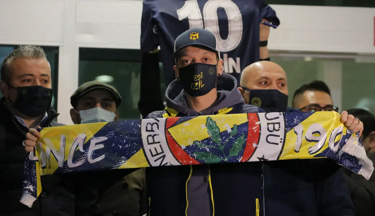 Gelandang Jerman, Mesut Ozil membentangkan syal klub barunya Fenerbahce setibanya di Bandara Ataturk di Istanbul (18/1/2021). Ozil yang merupakan keturunan Turki akan berusaha menghidupkan kembali karirnya setelah dia meninggalkan Arsenal. (AP Photo)