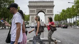 Orang-orang melintasi jalan Champs Elysees di Paris, Kamis (17/6/2021). Prancis mengumumkan melonggarkan aturan pembatasan COVID-19, mencabut aturan penggunaan masker di luar ruangan dan menghentikan jam malam mulai pekan ini setelah diberlakukan selama delapan bulan terakhir (AP Photo/Michel Euler)