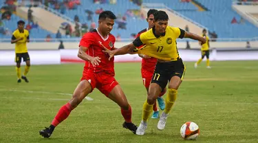 Gelandang Timnas Indonesia U-23, Asnawi Mangkualam berusaha merebut bola dari bek Malaysia, Muhammad Safwan bin Mazlan dalam pertandingan perebutan medali perunggu SEA Games 2021 di Stadion My Dinh, Minggu (22/5/2022). Indonesia ditahan imbang 1-1 dan menang 4-3 di adu penalti. (AFP/Tang Chhin Sothy)