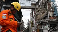 Petugas Basarnas berdiri dekat gedung yang ambruk di Jalan Brigjen Katamso, Kota Bambu Selatan, Palmerah, Jakarta Barat, Senin (6/1/2020). Tiga orang dilaporkan terluka akibat tertima material gedung empat lantai tersebut. (Liputan6.com/Johan Tallo)