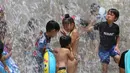 Anak-anak bermain di air di sebuah taman di Tokyo, Jepang, (16/7). Badan Meteorologi nmengatakan gelombang panas terus berlanjut di wilayah metro ketika suhu naik mencapai 35 derajat Celcius (95 derajat Fahrenheit). (AP Photo/Koji Sasahara)