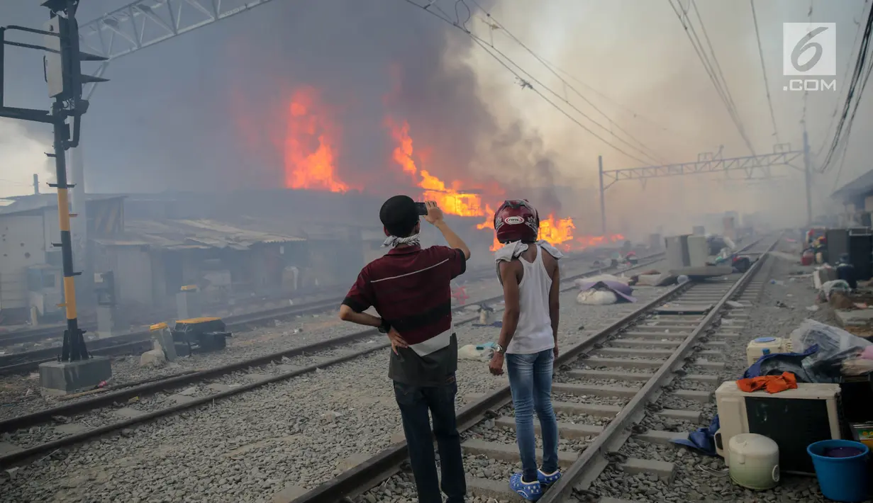 Warga mengambil gambar kebakaran yang melanda rumah semi permanen atau bedeng di belakang Hotel Alexis, Pademangan, Jakarta, Sabtu (16/9). Hingga saat ini, proses pemadaman kebakaran masih dilakukan petugas. (Liputan6.com/Faizal Fanani)