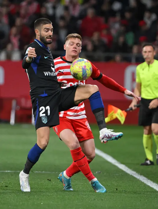 <p>Pemain Atletico Madrid Yannick Ferreira-Carrasco (kiri) bersaing memperebutkan bola dengan pemain Girona Viktor Tsygankov pada pertandingan sepak bola Liga Spanyol di Stadion Montilivi, Girona, Spanyol, 13 Maret 2023. Gol tunggal Alvaro Morata membawa Atletico Madrid mengalahkan Girona. (LLUIS GENE/AFP)</p>