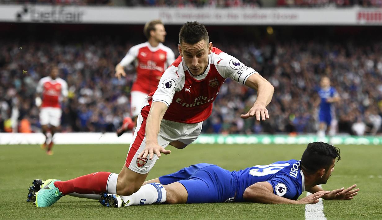 Pemain Arsenal, Laurent Koscielny terjatuh bersama pemain Chelsea, Diego Costa pada lanjutan Premier League di Emirates Stadium, Minggu (25/9/2016) dini hari WIB. (Reuters/Dylan Martinez)