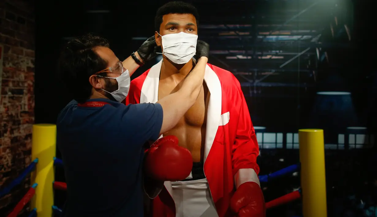 Pekerja mengenakan makser pada patung lilin legenda tinju dunia, Muhammad Ali di Madame Tussauds di Istanbul, Sabtu (11/7/2020). Dibuka kembali, sejumlah sosok tokoh terkenal di museum itu dipakaikan masker untuk meningkatkan kesadaran terhadap penyebaran Covid-19. (AP Photo/Emrah Gurel)