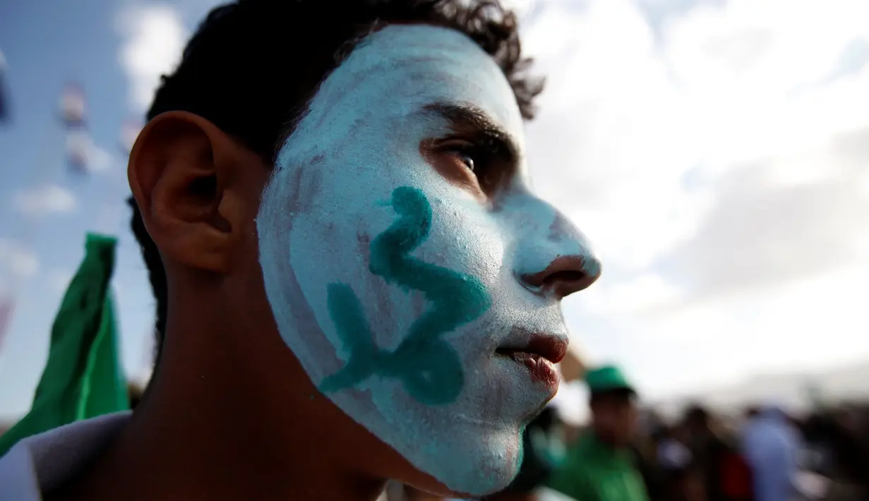 Seorang remaja dengan wajah yang dicat bertuliskan "Muhammad" mengikuti peringatan hari kelahiran Nabi Muhammad di Sanaa, Yaman (11/12). (Reuters/Khaled Abdullah)