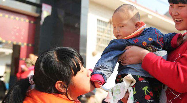 Guo mencium tangan seorang bayi anak tetangga. Guo senang sekali dengan anak kecil di sekitarnya | foto: copyright chinadaily.com.cn