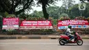Kendaraan melintasi karangan bunga yang menghiasi kawasan Patung Kuda, Jakarta, Kamis (15/10/2020). Karangan bunga tersebut merupakan apresiasi masyarakat kepada TNI-Polri yang telah menjaga keamanan saat demo. (Liputan6.com/Faizal Fanani)