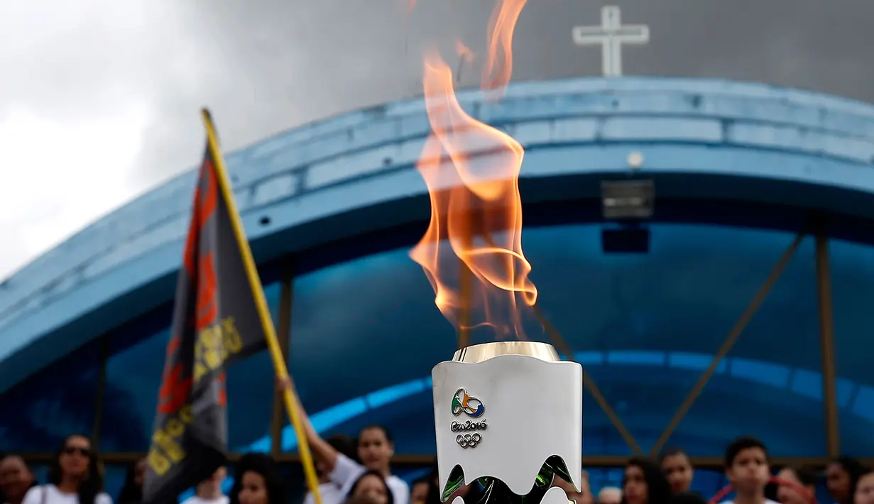 Warga menyaksikan parade obor Olimpiade yang melintas di Itamaraju, Kota Bahia , Brasil,(19/5/2016). Olimpiade akan dilaksanakan di Rio De Jeneiro.  (AFP/Marcos de Paula)