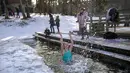 Seorang wanita mandi di lubang es di danau dekat Vilnius, Lithuania, Minggu (13/2/2022). Suhu udara 0 derajat Celcius (32 derajat Fahrenheit). (AP Photo/Mindaugas Kulbis)
