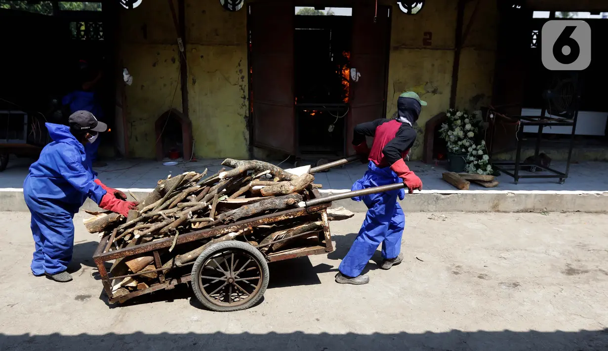 Petugas menyiapkan kayu bakar untuk proses kremasi jenazah di Krematorium Cilincing, Jakarta, Kamis (29/7/2021). Proses kremasi jenazah di Krematorium Cilincing masih menggunakan cara tradisional menggunakan kayu bakar dan membutuhkan waktu sekitar dua jam. (Liputan6.com/Helmi Fithriansyah)