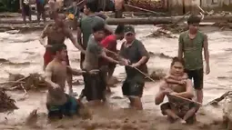 Warga menggunakan tali berusaha menolong korban banjir dahsyat yang melanda Lanao del Norte, Filipina selatan (22/12). Dikutip dari media Filipina, mengabarkan setidaknya 127 korban tewas dalam musibah ini. (Aclimah Disumala via AP)