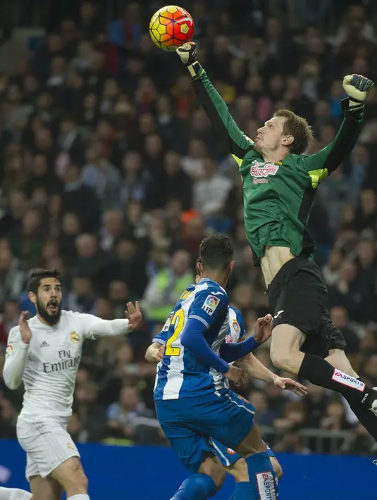 Kiper Espanyol, Giedrius Arlauskis, menepis bola sundulan pemain Real Madrid pada laga La Liga. Sementara bagi Espanyol hasil ini membuat mereka kian terpuruk di posisi ke-15. (AFP/Curto De La Torre)
