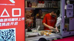 Seorang pria bekerja di toko kecil untuk dalgona, permen gula renyah yang ditampilkan dalam serial Netflix Squid Game, di Shanghai pada 12 Oktober 2021. Meski Netflix diblokir pemerintah China, tetapi serial Netflix Squid Game sukses meraih popularitas di Negeri Tirai Bambu itu. (Hector RETAMAL/AFP)
