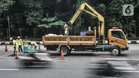 Pekerja melakukan pengaspalan jalan berlubang di Jalan DI Panjaitan, Cawang, Jakarta, Senin (25/1/2021). Perbaikan jalan rusak dan berlubang akibat sering tergenang banjir di kawasan tersebut dilakukan untuk mengantisipasi terjadinya kecelakaan pengendara. (merdeka.com/Iqbal S Nugroho)