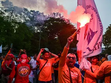 Seorang pengunjuk rasa menyalakan suar dalam aksi unjuk rasa peringatan Hari Buruh Internasional (May Day) di Surabaya, Jawa Timur, pada Kamis 1 Mei 2025. (Juni KRISWANTO/AFP)