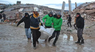 Penyelamat Suriah membawa jenazah melewati bangunan yang runtuh saat operasi pencarian berlanjut setelah gempa mematikan di kota Sarmada, di provinsi Idlib barat laut yang dikuasai pemberontak Suriah pada 6 Februari 2023. Setidaknya 1.400 orang tewas dan 3.411 terluka di seluruh Suriah hari ini dalam gempa bumi yang berpusat di Turki barat daya, kata pemerintah dan penyelamat. (AFP/Aaref Watad)