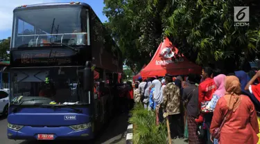 Antrean warga menaiki bus tingkat untuk wisata keliling Ibu Kota di depan Masjid Istiqlal, Jakarta, Sabtu (31/3). Libur tiga hari di penghujung Maret 2018 dimanfaatkan untuk berkeliling Jakarta menggunakan bus tingkat City Tour. (Merdeka.com/Imam Buhori)