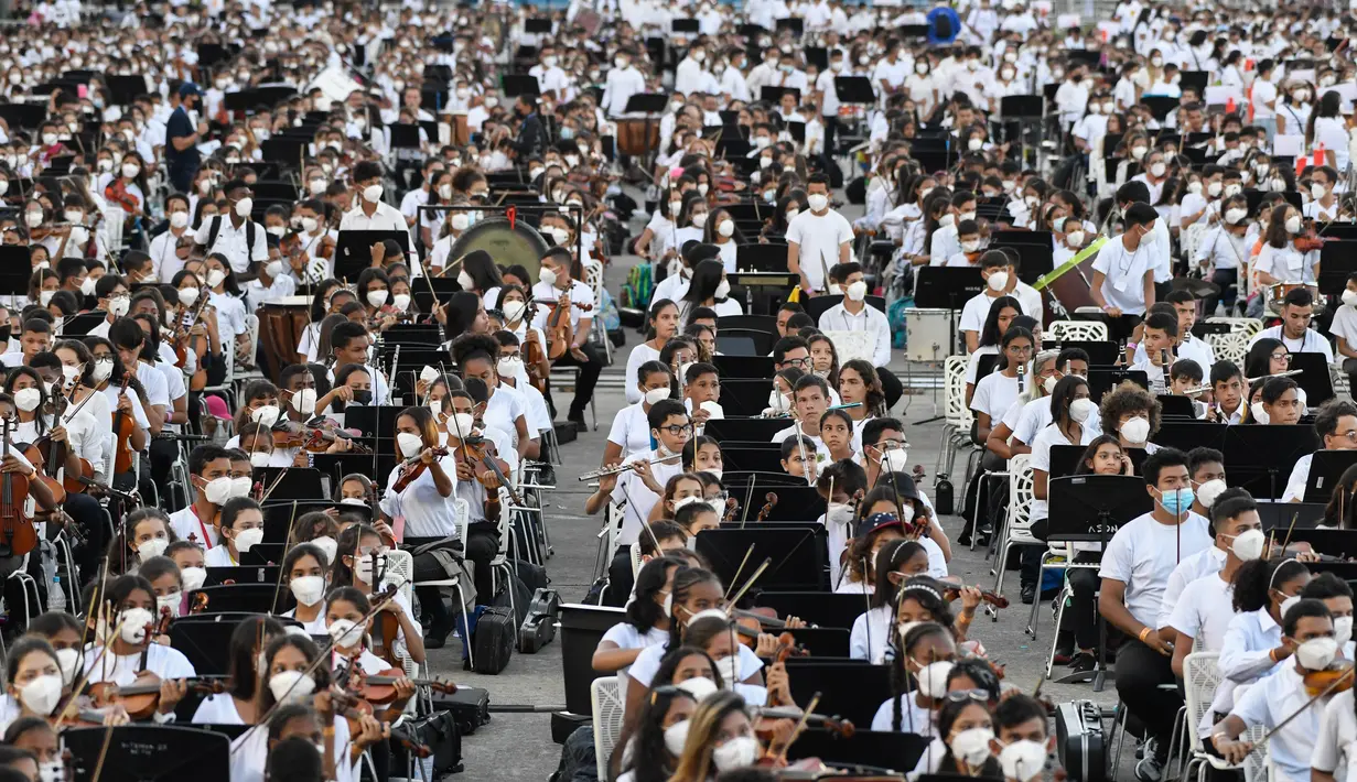 Musisi dari National System of Orchestras of Venezuela berusaha memecahkan rekor dunia bermain orkestra terbesar di dunia, di Caracas pada 13 November 2021. Para musisi berusia antara 12 dan 77 tahun itu kompak mengenakan celana hitam, kemeja putih, dan masker. (Federico PARRA/AFP)