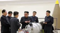 Pemimpin Korut, Kim Jong-un berbincang dengan para peneliti mengenai program senjata nuklir saat meninjau pembuatan bom hidrogen yang dapat dimasukkan ke dalam rudal balistik antarbenua pada 3 September 2017. (AFP Photo/Kcna Via Kns/Str)