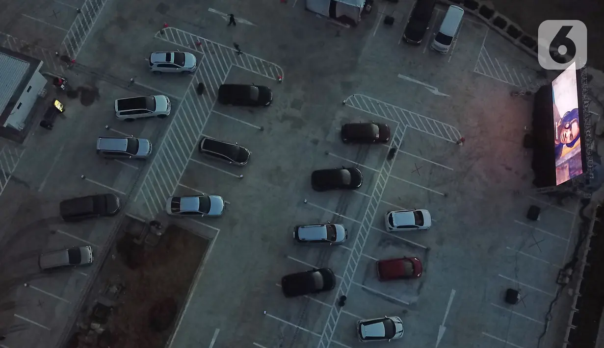 Foto dari udara menunjukkan deretan mobil penonton terparkir saat menyaksikan pemutaran film secara drive-in di Cikarang, Bekasi, Jawa Barat, Rabu (3/6/2020). Kehadiran drive-in cinema memberikan hiburan alternatif kepada warga di tengah pandemi virus corona COVID-19. (Liputan6.com/Herman Zakharia)