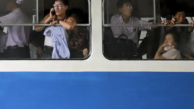 Seorang pria berbicara lewat telepon genggamnya saat ia dan penumpang lain tengah naik kereta listrik di pusat kota Pyongyang (AP)