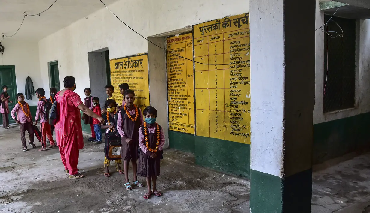 Guru menyambut siswa dengan karangan bunga di sebuah sekolah di Allahabad, India, Rabu (1/9/2021). Pemerintah negara bagian melonggarkan lockdown COVID-19 untuk lembaga pendidikan yang memungkinkan siswa menghadiri sekolah tatap muka dengan 50 persen kapasitas. (SANJAY KANOJIA/AFP)