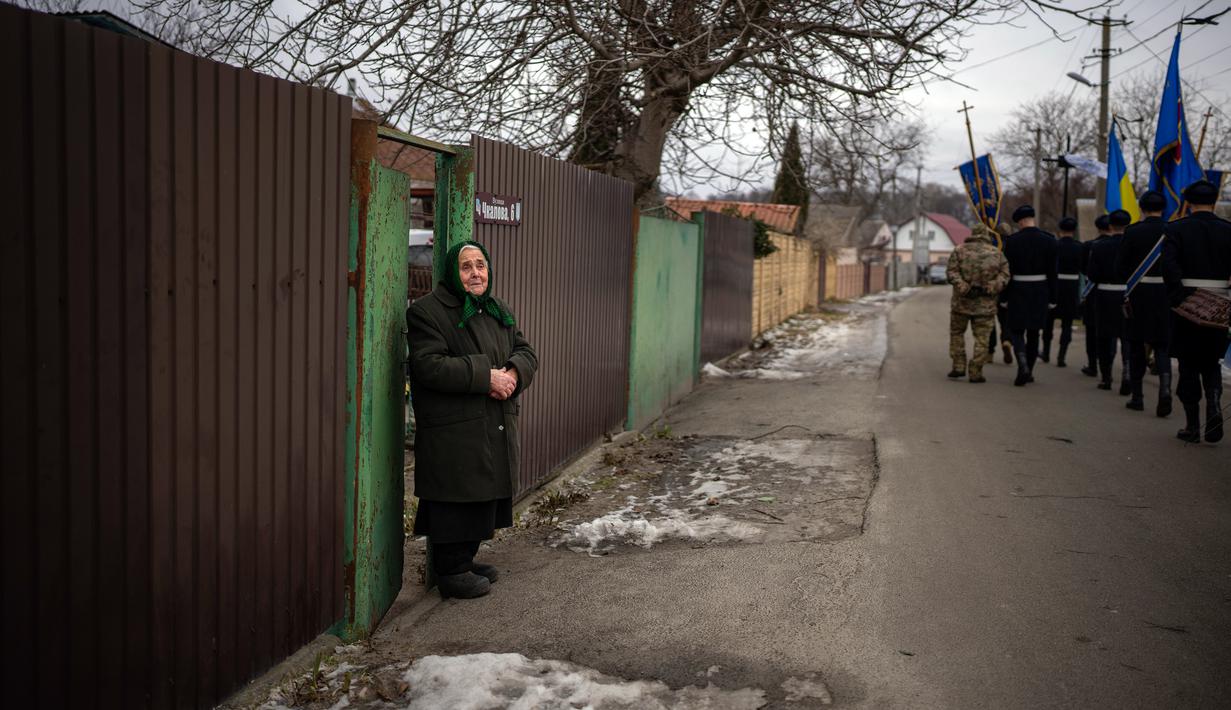 Olha Petrenko (84) menangis saat peti mati Oleksandr Maksymenko (38) lewat pada pemakamannya di kampung halamannya di Kniazhychi, sebelah timur Kyiv, Ukraina, 13 Februari 2023. Oleksandr Maksymenko, seorang warga sipil yang menjadi sukarelawan di angkatan bersenjata Ukraina, tewas dalam pertempuran di daerah Bakhmut. (AP Photo/Emilio Morenatti)
