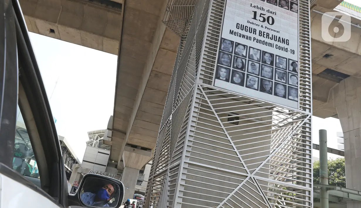 Pengendara melintasi videotron penghormatan kepada tenaga medis yang gugur akibat Covid-19 di tiang penyangga lintasan MRT, Jalan Sisingamangaraja, Jakarta, Jumat (18/9/2020). Masyarakat diharapkan selalu menjaga protokol kesehatan saat berada di luar ruangan. (Liputan6.com/Herman Zakharia)