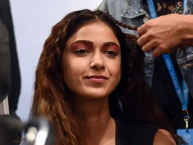 Seorang model saat ditata rambutnya oleh kru makeup di belakang panggung sebelum tampil di catwalk selama Lakmé Fashion Week (LFW) Summer Resort 2019 di Mumbai, India (31/1). (AFP Photo/Sujit Jaiswal)