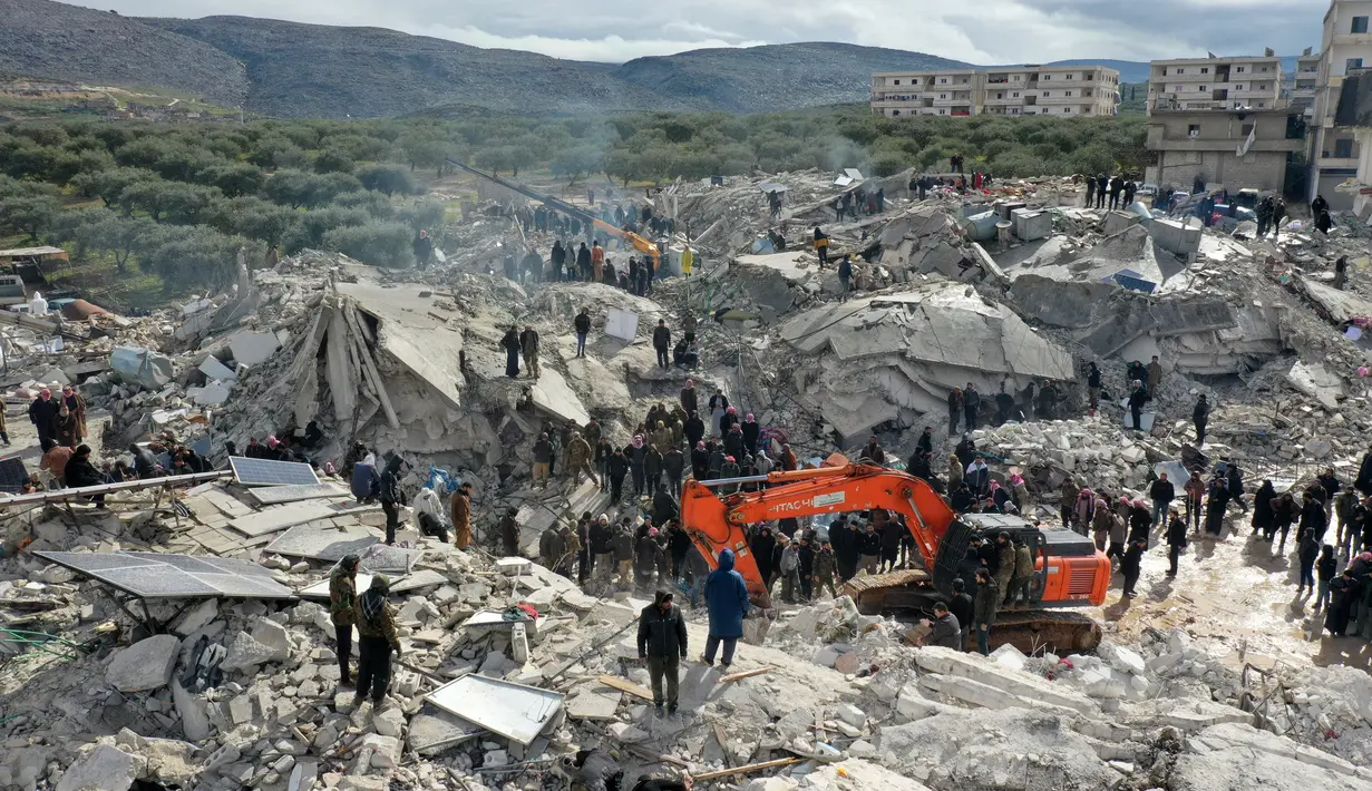 Pemandangan dari udara ini menunjukkan penduduk mencari korban dan penyintas di tengah puing-puing bangunan yang runtuh setelah gempa bumi di desa Besnia dekat Harim, di provinsi Idlib barat laut yang dikuasai pemberontak Suriah di perbatasan dengan Turki, Senin (6/2/2023). Dilansir AFP, Selasa (7/2) setidaknya 1.444 orang tewas pada Senin (6/2) di seluruh wilayah Suriah, kata pemerintah dan otoritas penyelamat setempat. (Omar HAJ KADOUR / AFP)