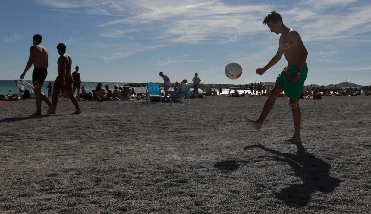 Seorang anak bermain bola di tepi Pantai Prado yang merupakan salah satu garis pantai yang sering dijadikan turis untuk berjemur. (Bola.com/Vitalis Yogi Trisna)
