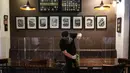 Pekerja membersihkan papan pelindung akrilik usai digunakan pengunjung di The Atjeh Connection Coffee and Resto, Jakarta, Senin (8/6/2020). Tempat ini siap menerapkan protokol kesehatan dalam menerapkan tatanan kehidupan baru atau ‘new normal’. (Liputan6.com/Faizal Fanani)