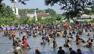 Ratusan penduduk antusias mengikuti aktivitas ngubek empang dalam penyelenggaraan Lebaran Depok di wilayah Pengasinan, Depok. (detikai.com/Dicky Agung Prihanto)