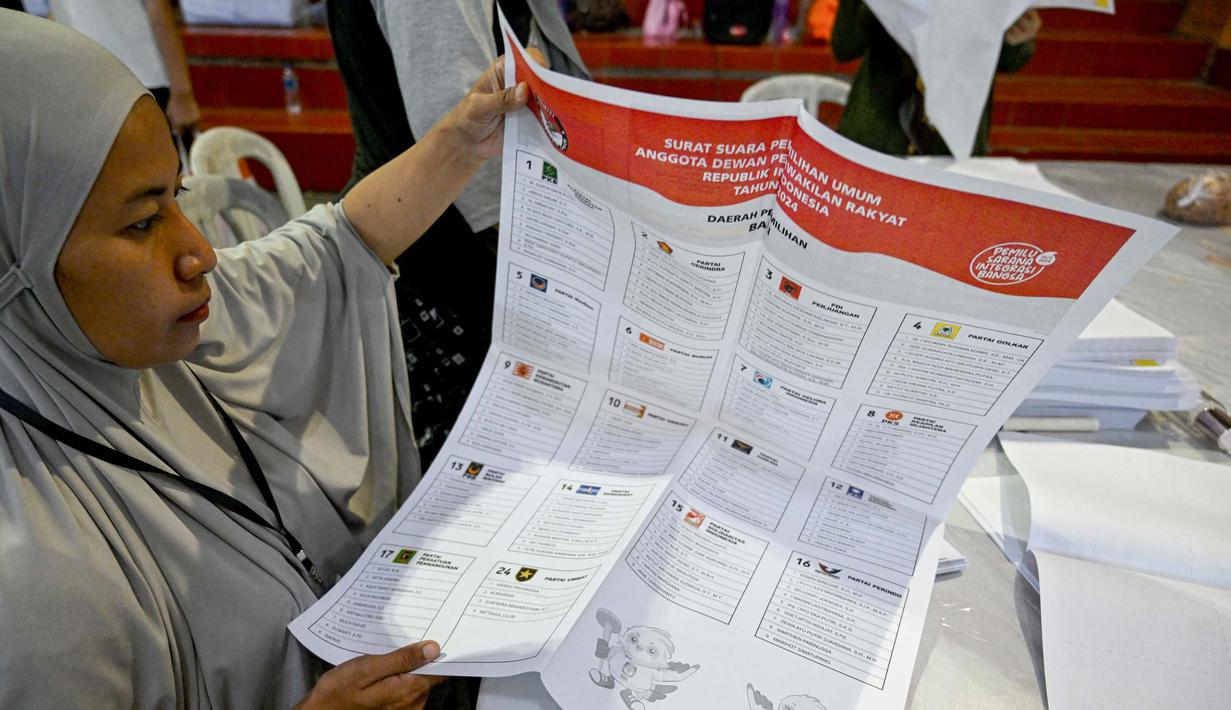 Para staf melipat surat suara pemilihan umum Indonesia 2024 di Gudang Logistik Komisi Pemilihan Umum (KPU) Denpasar, Bali, pada 14 Desember 2023. (SONNY TUMBELAKA/AFP)