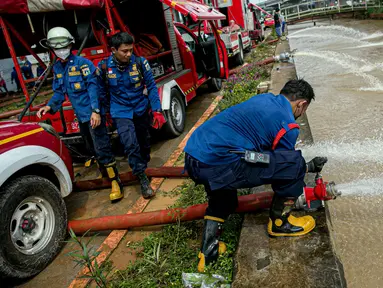 Petugas pemadan kebakaran menyedot air banjir di kawasan Cipinang Melayu, Jakarta, Minggu (21/2/2021). Suku Dinas Pemadam Kebakaran Jakarta Timur mengerahkan 20 mobil pompa untuk menyedot air yang membanjiri RW 04 Kelurahan Cipinang Melayu untuk mengurangi debit air. (Liputan6.com/Faizal Fanani)